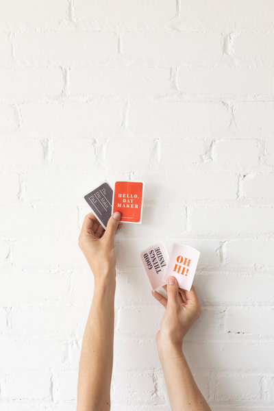 Hands holding up business cards on a white brick background